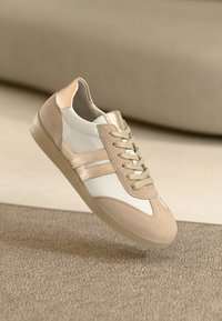 Beige and white sneakers feature a smooth leather upper, suede accents, two lateral stripes, and flat laces. Textured rubber sole.