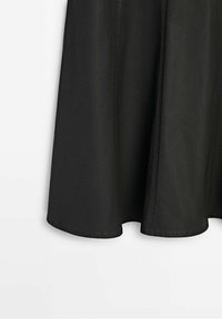 Gonna nera in tessuto liscio con taglio svasato, caratterizzata da cuciture visibili e orlo arrotondato.