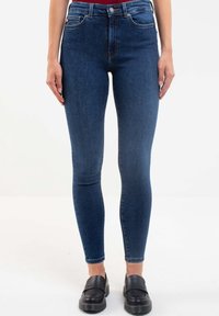 Slim-fit jeans i mörkblå denim, hög midja, femfickorsdesign, med bälteshällor och en liten märkesetikett på bakfickan.