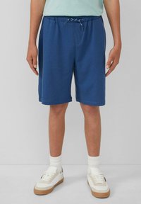 Blauwe katoenen shorts met een elastische tailleband en trekkoord, voorzien van zijzakken en een relaxte pasvorm, gecombineerd met witte sneakers en geribde sokken.