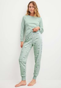 Lichtgroene lange mouwen top gecombineerd met joggerbroeken met een patroon van kleine dieren. Soepele stof, comfortabele pasvorm, enkelmanchetten.