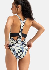 Maillot de bain en tissu à motifs avec un design floral bleu, blanc et vert, présentant un dos nageur et un dos ouvert avec une bande noire contrastante.