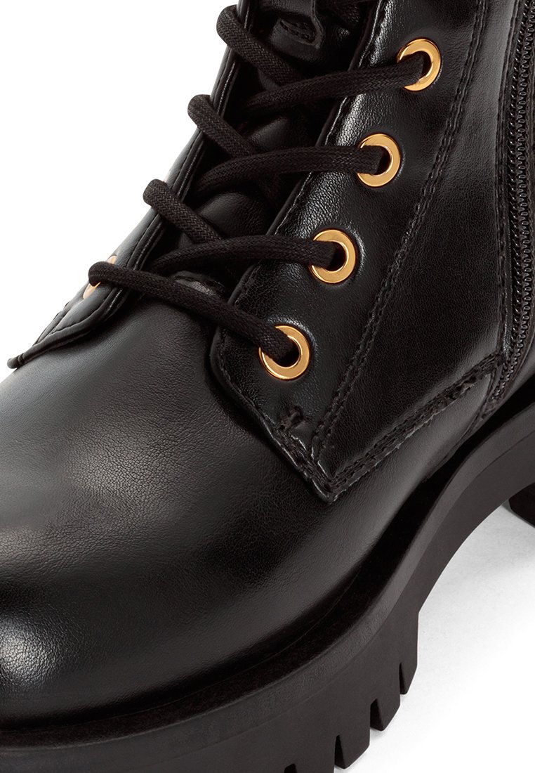 Schwarze Leder-Ankle-Boots mit goldfarbenen Ösen, schwarzen Schnürsenkeln, einem seitlichen Reißverschluss und einer dicken, strukturierten Gummisohle.