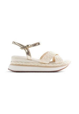 Sandale plateforme avec brides croisées tissées crème, bride de cheville métallique avec boucle, et semelle blanche épaisse avec détail tressé au-dessus de la semelle.