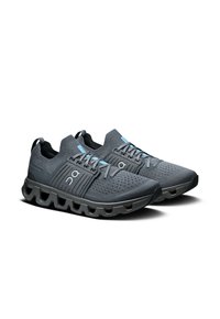 Chaussures de sport grises avec une tige en mesh respirant, accents en bleu clair contrastants, semelle arrondie avec de multiples rainures et des détails texturés.