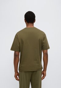 Χακί πράσινο βαμβακερό κοντομάνικο μπλουζάκι, άνετη εφαρμογή με στρογγυλή λαιμόκοψη, ορατές ραφές και απαλή υφή.