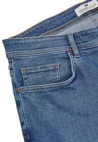 Vaqueros de denim azul con un corte recto clásico, que cuentan con un bolsillo frontal y un bolsillo trasero con detalles de costura y una etiqueta de logo en la cinturilla.