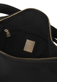 Notranjost črne usnjene torbice z zlatim zadrgo. Ima osrednji žep na zadrgo in majhno pravokotno oznako z logotipom. Mehak občutek.