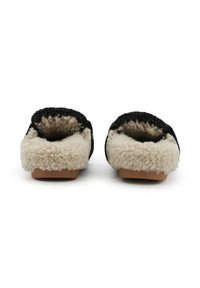 Pantofole nere e beige con una morbida fodera interna pelosa, forma curva e suola piatta, caratterizzate da un bordo superiore testurizzato.