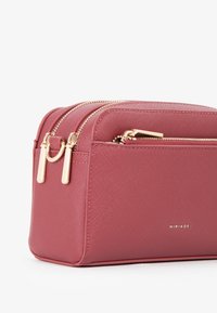 Borsa cosmetica rettangolare e strutturata di colore rosa scuro, realizzata in materiale testurizzato. Presenta doppie cerniere dorate e un logo discreto.