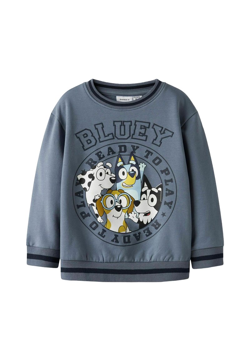 Pilkas džemperis su apvaliu spaudiniu, kuriame pavaizduoti animaciniai šunys ir užrašas "BLUEY READY TO PLAY". Pakietintos rankovės ir apykaklė. Minkšta medžiaga, laisvalaikio stilius.