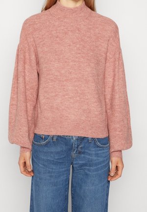 Pink, ribbed knit sweater with a high neck and balloon sleeves, paired with blue wide-leg jeans. Soft texture and casual fit.