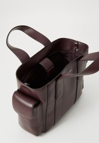 Bordo odinės rankinės su plokšiomis rankenomis, atviru viršumi, vidinėmis kišenėmis ir šonine kišene su dangteliu. Lygi tekstūra su elegantiškais siuvimo detalėmis.