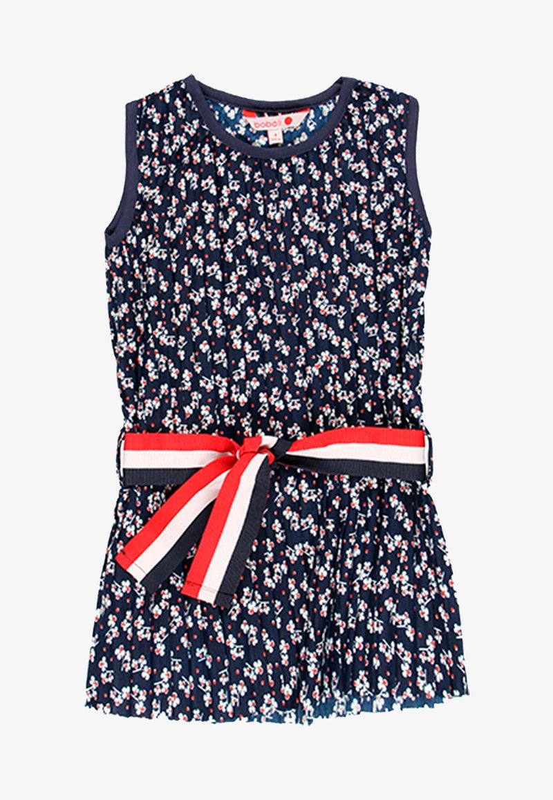 Robe sans manches de couleur marine avec un petit imprimé floral blanc et rouge et une jupe plissée, nouée à la taille avec une ceinture nœud rayée rouge, blanche et marine.