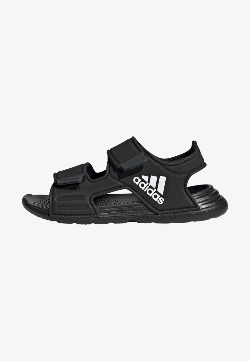 Chaussons de sport noirs en matériau synthétique, dotés de deux sangles Velcro réglables et d'une semelle perforée pour la ventilation.