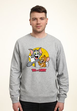 Gray sweatshirt featuring a colorful print of Tom and Jerry against a yellow circle, with logo text below. Soft fabric, ribbed cuffs.