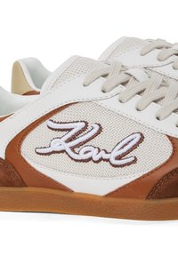 Fehér sneakers barna bőr részletekkel, hálós panelek és bézs fűzők. Hímzett logó barna színben. Texturált gumi talp.