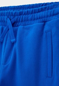Blå bomullsshorts med elastisk midja och dragsko samt sidofickor, med en slät textur och enhetlig färg.