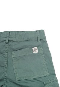 Grønne bomuldsshorts med en firkantet lomme og et logo-label. Stoffet har en glat tekstur og forstærkede sømme.