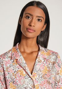Floral Schlafanzug-Oberteil aus leichtem Gewebe. Verfügt über ein Muster in Pink, Orange und Grau mit einem Reverskragen und weißen Paspeln entlang der Kanten.