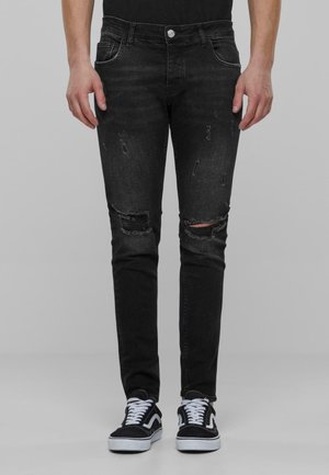 Jeans noirs slim fit avec des détails déchirés et des genoux déchirés, fabriqués en tissu denim. Comprend un bouton à la taille et des poches.