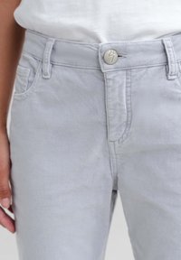 Lichtgrijze spijkerbroeken van een zachte katoenmix, met knoopsluiting, riemlussen en zijzakken. Zachte textuur met minimale stiksels.