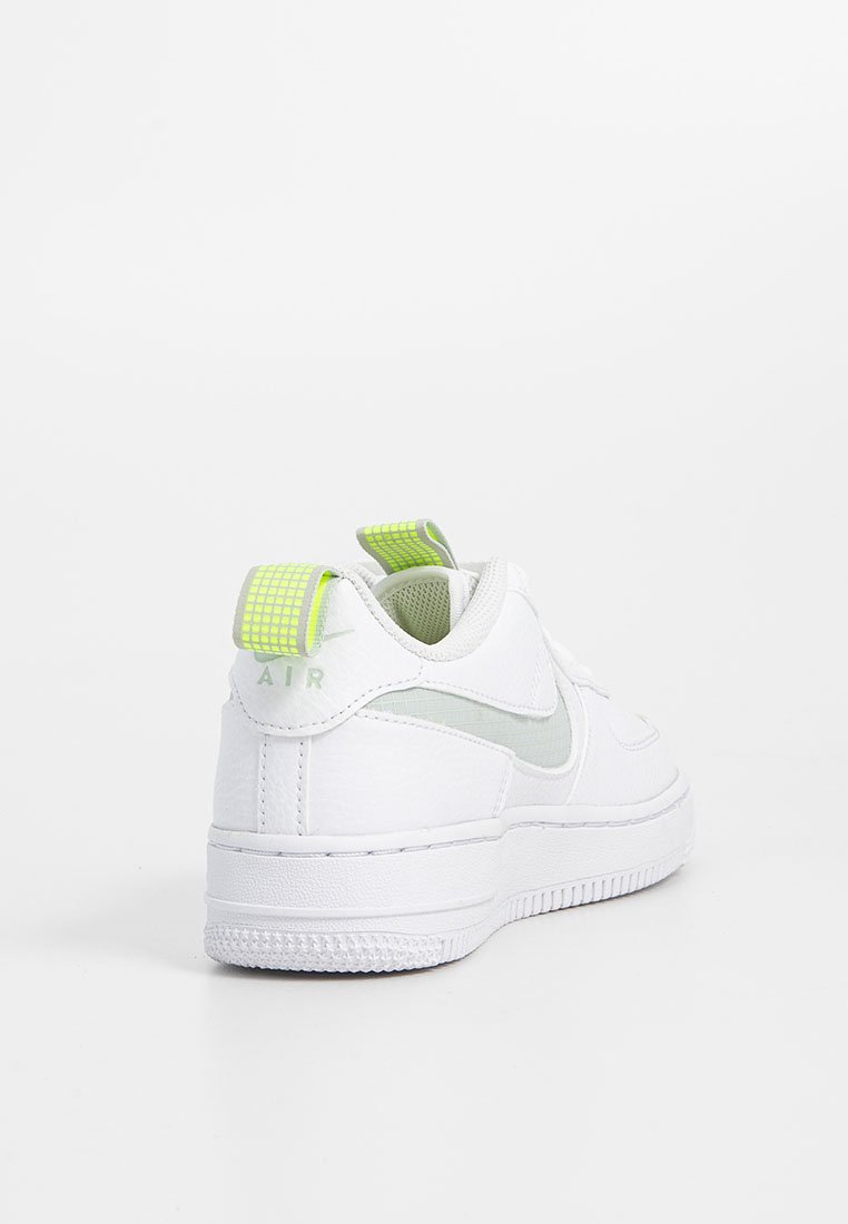 Baskets Nike Air blanches avec des tirants en grid jaune fluo à l'arrière et sur la languette, semelle texturée et détail en Swoosh sur le côté, tournées vers l'arrière sur fond blanc.