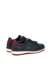 Zapatillas de cuero navy con acentos en burdeos en el talón, media suela blanca y cordones redondos. Acabado texturizado con el logo de la marca en el talón.