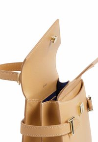 Borsa in pelle tan con una texture liscia, hardware dorato e un ampio interno dotato di una fodera in tessuto scuro e numerosi scomparti.