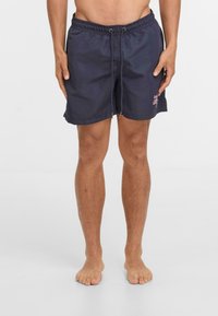 Jūras bruņniecības peldbikses ar elastīgu jostu, auklu un sānu kabatām; uz kreisās puses ir rozā logo druka.