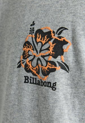 Gray fabric t-shirt featuring a black and orange hibiscus flower design with the word "Billabong" below in a bold font.