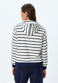 Gestreepte capuchontrui in crème en marineblauw, met horizontale strepen, een trekkoordkap en ribgebreide manchetten en zoom.