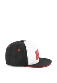 Casquette noir et blanc avec une visière plate, présentant un accent rouge sur le bord et un patch logo rouge rectangulaire à l'avant.