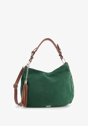 Grüne Wildleder-Handtasche mit geschwungener Form, braunem Ledertragegurt, silberner Hardware und einem dekorativen Quastenanhänger an der Seite.