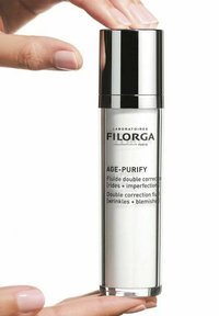 Clear glass serum bottle with silver pump top. Label reads "Filorga Age-Purify," detailing use against wrinkles and blemishes.