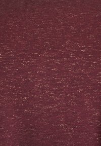 Bordo tkanina z ugođenim zaključkom s suptilnim zlatnim točkicama, koja stvara točkasti izgled i mekan, gladak osećaj.