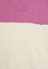 Kappa sweatshirt med fargeblokker design i rosa og krem, laget av mykt stoff med teksturert finish og logodetalj på brystet.