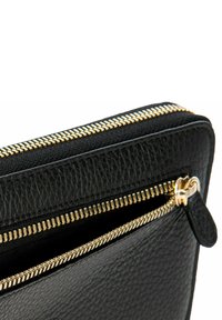 Cartera de cuero negro con una superficie texturizada, que presenta una cremallera dorada y un tirador, y un bolsillo visible en el interior.