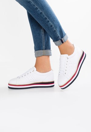 Hvide sneakers med runde tæer, glat lædermateriale og en flersfarvet platformsål med røde, hvide og blå striber.
