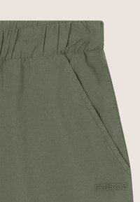 Pantaloni verde oliva in tessuto testurizzato, con girovita elastico, tasche laterali e logo in rilievo sul lato sinistro in basso.