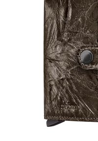 Donkere bruine leren portemonnee met een gerimpelde textuur, een druksluiting met een ronde zwarte knop en geÃ«mbossede branding.