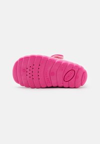 Suela de zapato para niña pequeña en color rosa, con perforaciones transpirables, surcos flexibles y la marca "Geox" grabada en la parte inferior.