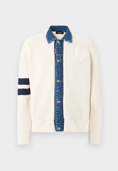 Cardigan en maille crème avec patte de boutonnage en denim bleu et col assorti, deux bandes noires sur la manche gauche, et logo "D2" en relief sur la poitrine.