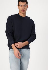 Sudadera de cuello redondo en tejido texturizado, con puños y dobladillo acanalados. Combínala con jeans azul claro para un look casual.