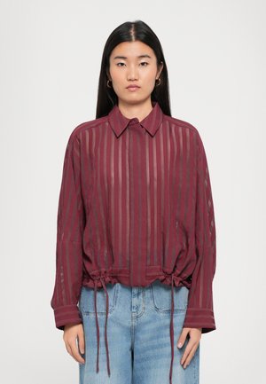 Maroon striped blouse with a collared neckline, gathered waist, and drawstring accents. Long sleeves with open weave details.