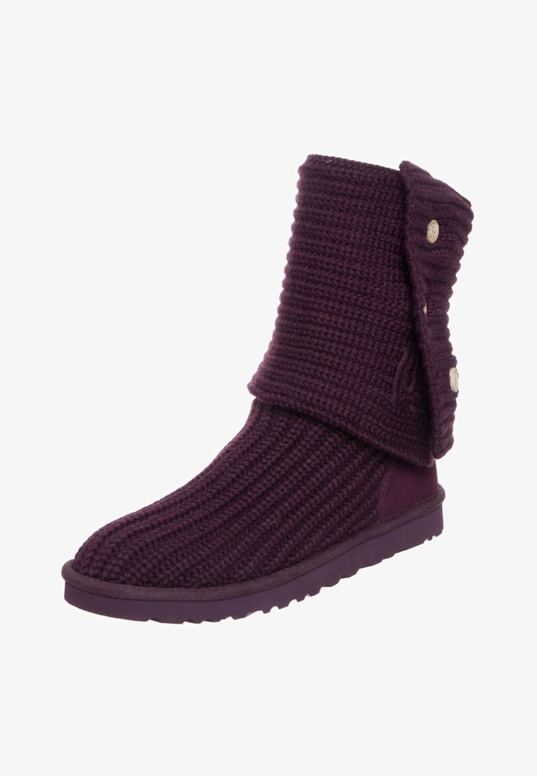 Botín de punto morado con un puño doblado, botones decorativos y suela de goma. El textil presenta un patrón acanalado para añadir textura.