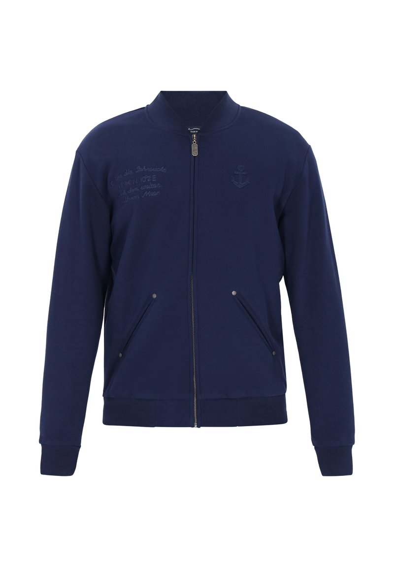 Marinblå zip-up-jacka i mjukt tyg med ståkrage, två framfickor och en ankringslogotyp broderad på bröstet.