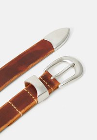 Brown leather belt with silver metal buckle, loop, and tip on a white background, showing detailed stitching and texture.