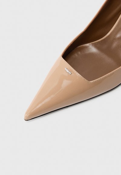 Nude lakasti salonar z ostrim prstom in kvadratnim izrezom, notranjost je gladka rjava, na strani pa ima majhen kovinski okras.