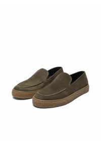 Zamszowe buty wsuwane w oliwkowym kolorze z okrągłym czubkiem, kontrastującą brązową gumową podeszwą i bez widocznych sznurowadeł czy zapięć.